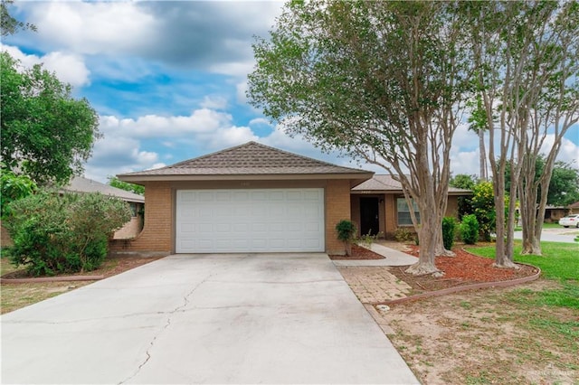 single story home featuring driveway, brick siding, and an attached garage