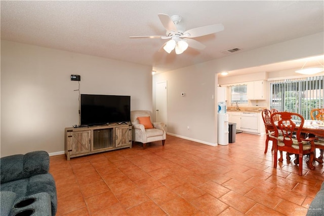 living room with a ceiling fan, visible vents, and baseboards
