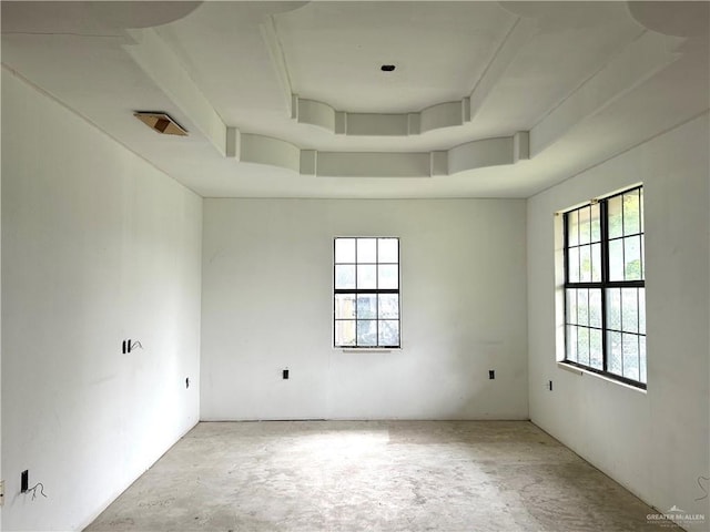 unfurnished room with a raised ceiling and concrete flooring