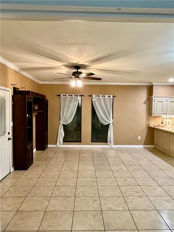 tiled spare room featuring ceiling fan and ornamental molding