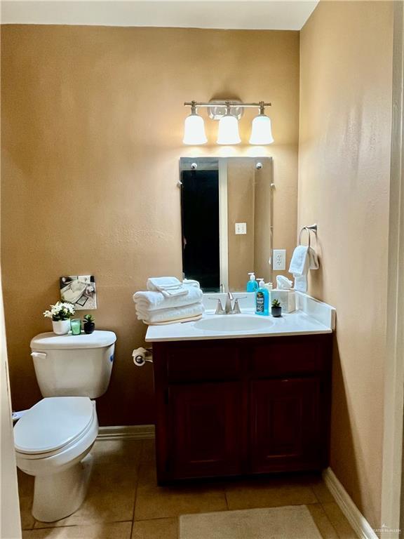 bathroom with toilet, vanity, and tile patterned flooring