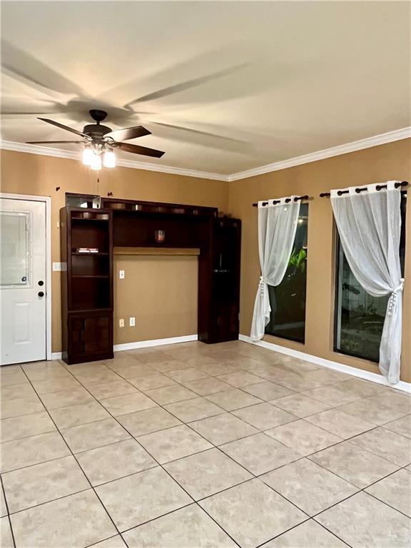 tiled spare room featuring ceiling fan and crown molding