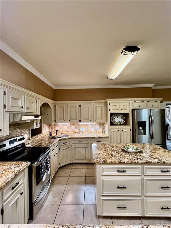 kitchen with appliances with stainless steel finishes, backsplash, light tile patterned flooring, light stone countertops, and sink