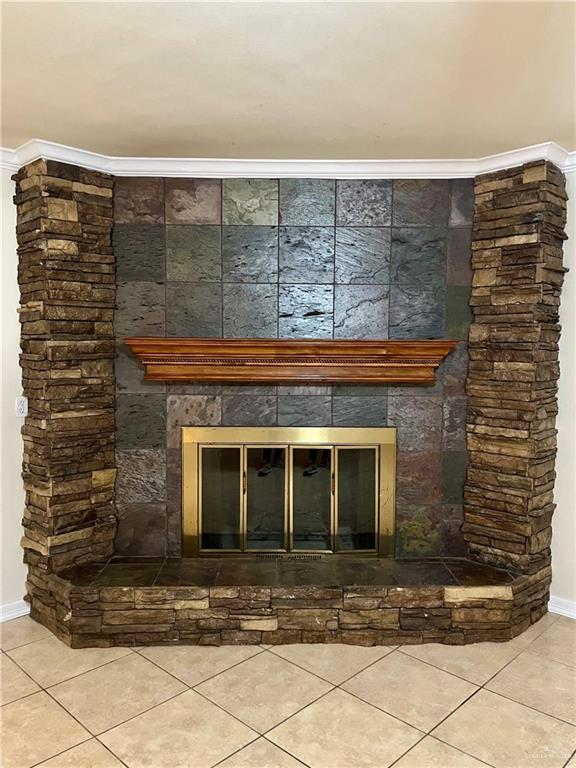 interior details with a stone fireplace and ornamental molding