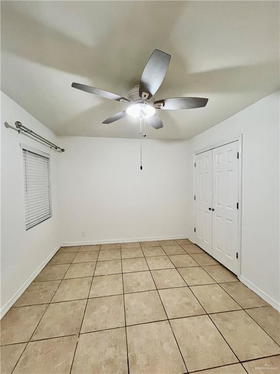 tiled spare room with ceiling fan