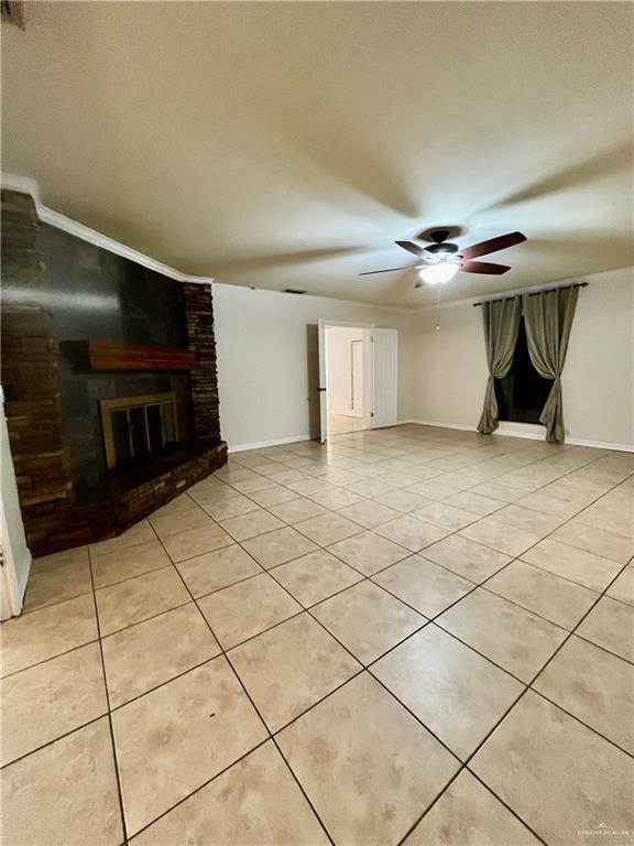 unfurnished living room featuring ceiling fan, light tile patterned floors, and a fireplace