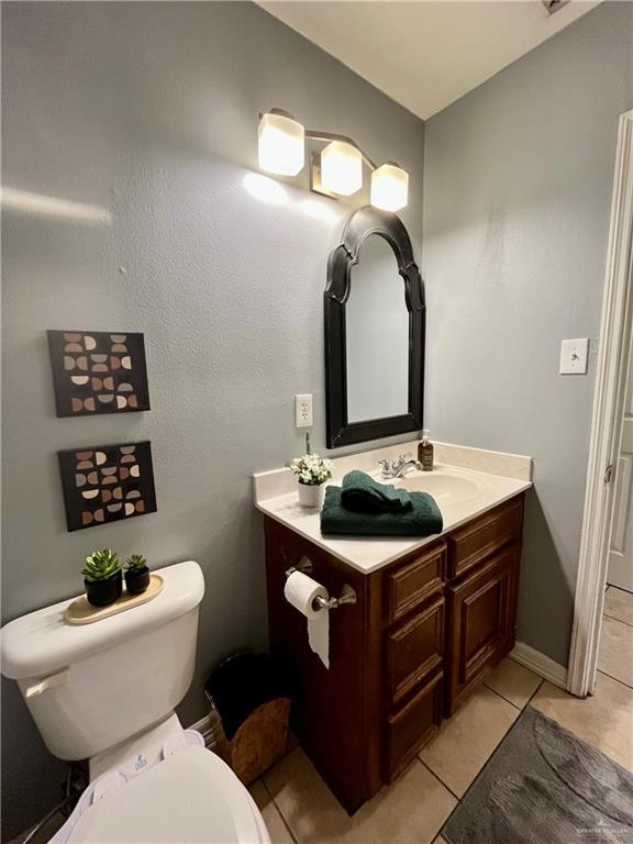 bathroom with toilet, vanity, and tile patterned floors