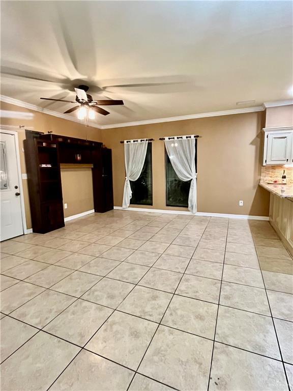 tiled empty room with ceiling fan and ornamental molding