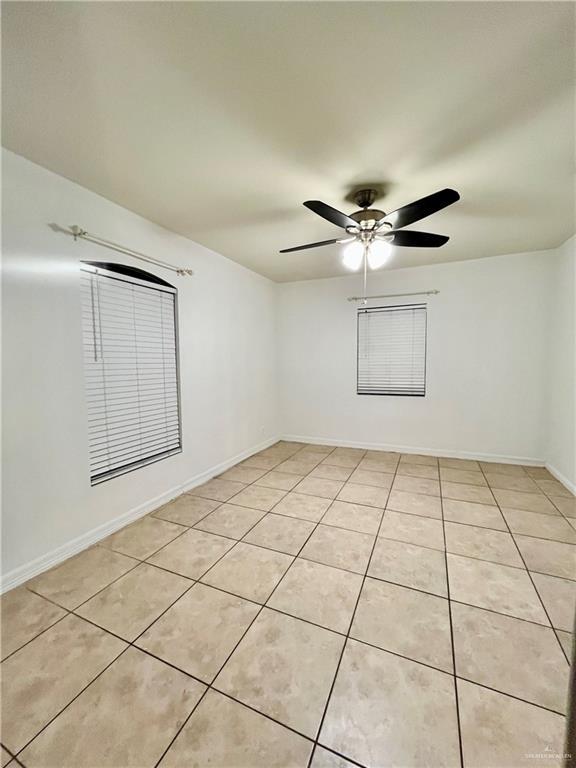 tiled spare room with ceiling fan