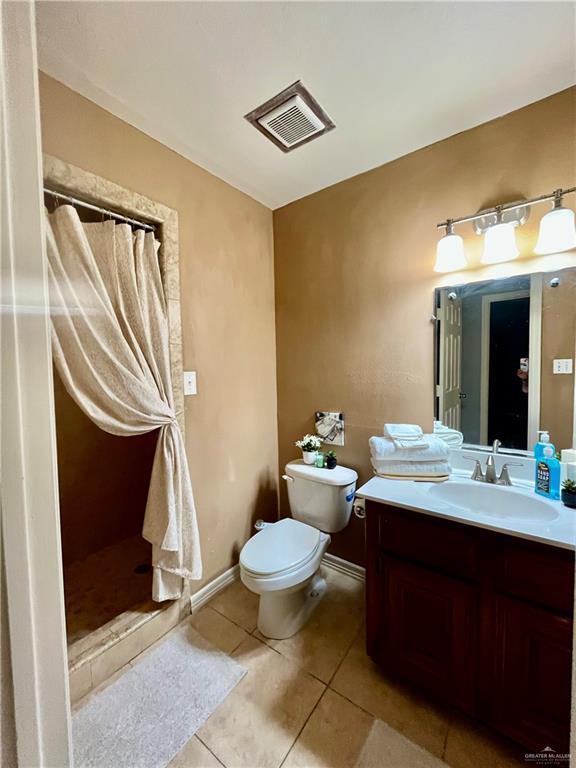 bathroom featuring toilet, a shower with curtain, tile patterned floors, and vanity