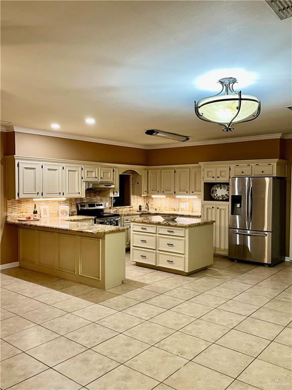 kitchen with light stone countertops, crown molding, light tile patterned floors, and stainless steel appliances