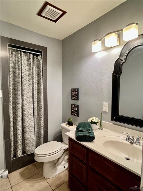 bathroom featuring toilet, a shower with curtain, and tile patterned floors