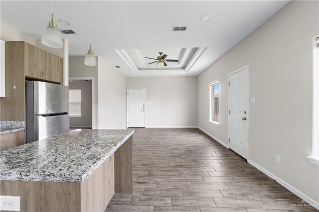 912 Kentucky St, Alton, TX 78573 - kitchen with freestanding refrigerator, a ceiling fan, a tray ceiling, wood finished floors, and light stone counters
