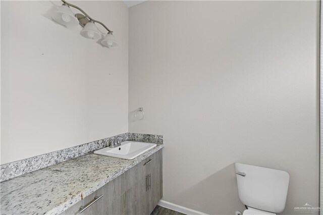 912 Kentucky St, Alton, TX 78573 - bathroom with toilet, vanity, wood finished floors, and baseboards