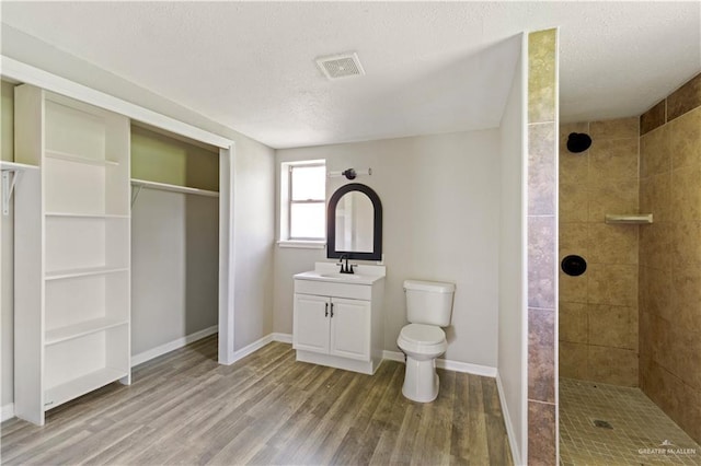 1125 W Schunior St, Edinburg, TX 78541 - bathroom with wood finished floors, a tile shower, vanity, a textured ceiling, and a spacious closet
