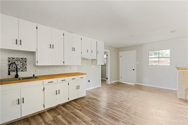 1125 W Schunior St, Edinburg, TX 78541 - kitchen featuring decorative backsplash, light wood-type flooring, white cabinets, and butcher block countertops