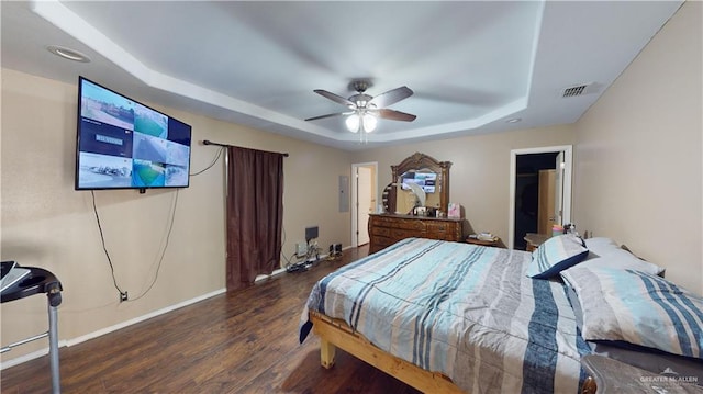 bedroom with a raised ceiling, electric panel, ceiling fan, and dark hardwood / wood-style flooring