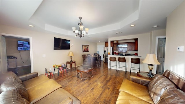 living room featuring a chandelier, hardwood / wood-style floors, and a tray ceiling