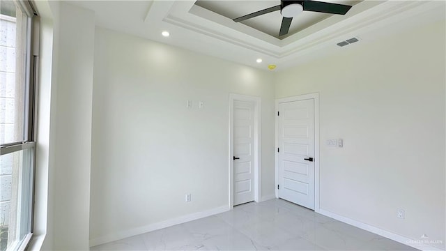 unfurnished room featuring a tray ceiling, ceiling fan, and plenty of natural light