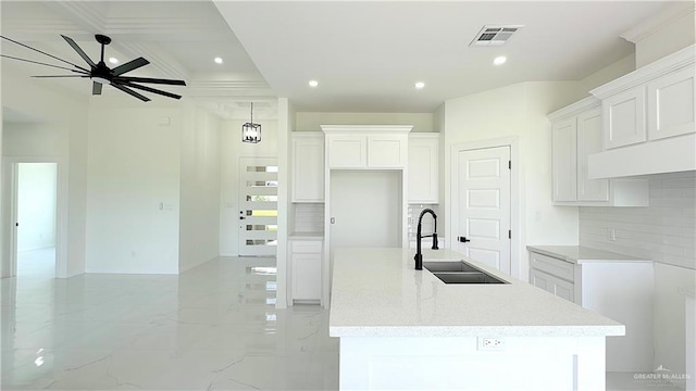 kitchen featuring tasteful backsplash, a large island with sink, white cabinetry, and sink