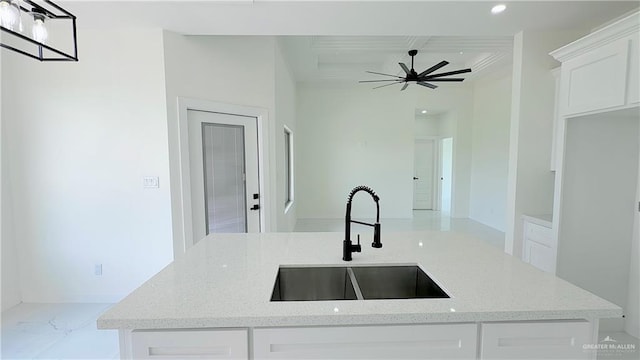 kitchen with light stone countertops, white cabinetry, and sink