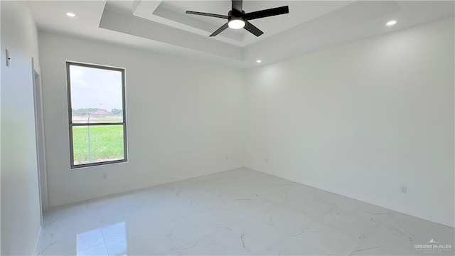 empty room featuring a tray ceiling and ceiling fan