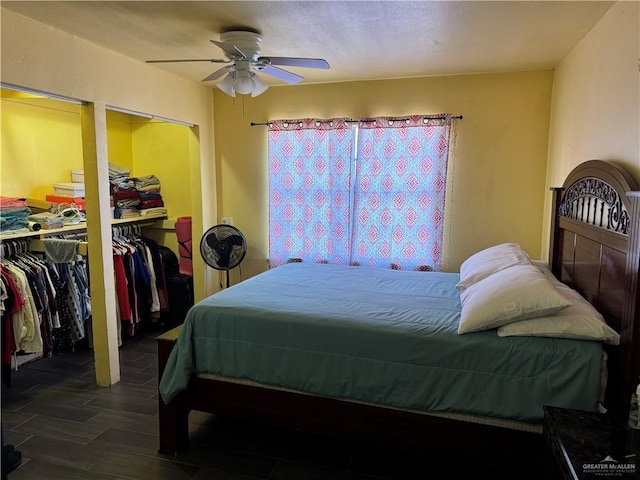 bedroom featuring multiple closets, a ceiling fan, and wood finished floors