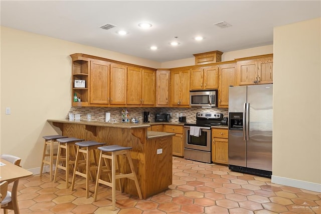 kitchen with stainless steel appliances, a kitchen breakfast bar, backsplash, kitchen peninsula, and light tile patterned flooring