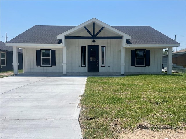 209 S Raul Longoria Rd, Edinburg, TX 78542 - view of front facade with covered porch, a shingled roof, board and batten siding, and a front lawn