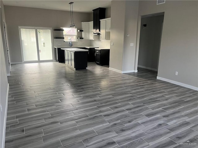 kitchen with dark wood-style floors, pendant lighting, tasteful backsplash, open floor plan, and a kitchen island