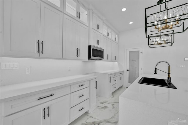 kitchen with marble finish floor, recessed lighting, stainless steel microwave, glass insert cabinets, and a sink