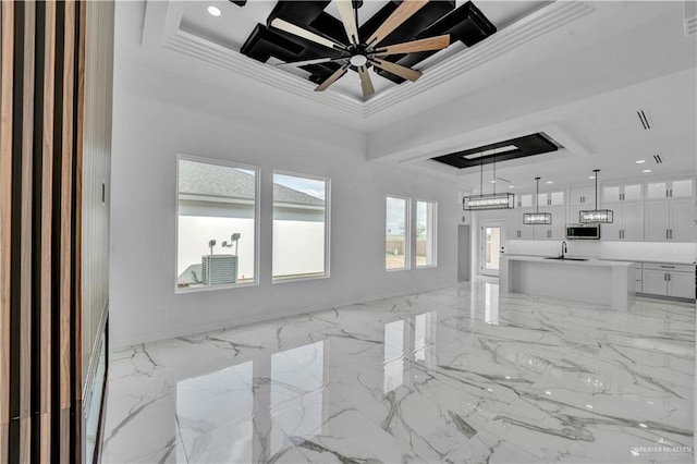 living area featuring marble finish floor, a ceiling fan, a tray ceiling, and crown molding