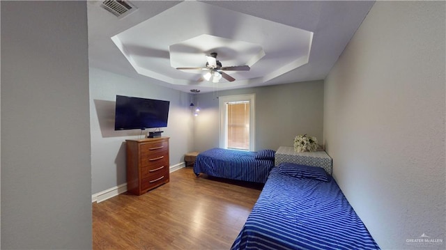 bedroom featuring hardwood / wood-style floors, ceiling fan, and a raised ceiling