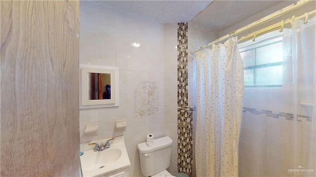 bathroom with a textured ceiling, vanity, tile walls, toilet, and curtained shower