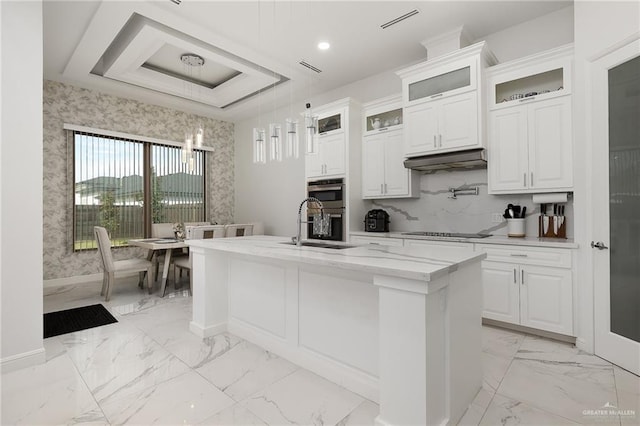 kitchen with hanging light fixtures, black electric cooktop, white cabinetry, and a kitchen island with sink