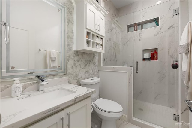 bathroom with a shower with door, vanity, and toilet