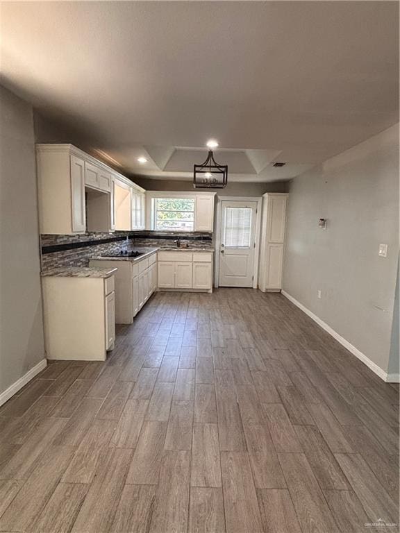 1012 S Inspiration Rd, Mission, TX 78573 - kitchen featuring baseboards, wood finished floors, white cabinets, a sink, and decorative backsplash