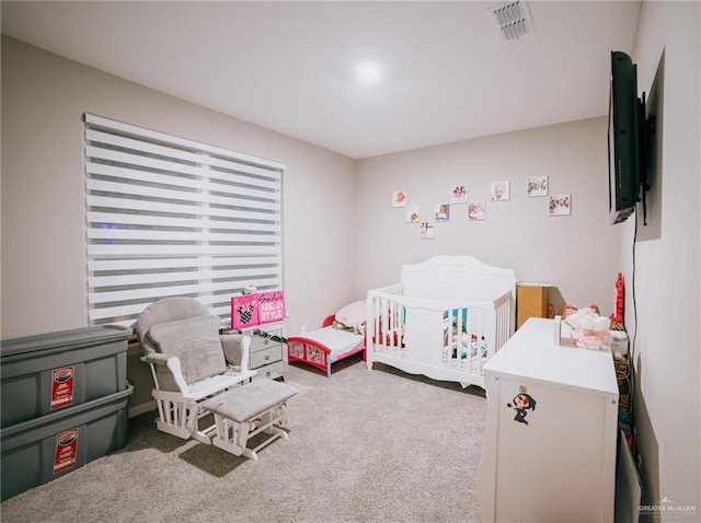 carpeted bedroom featuring a nursery area