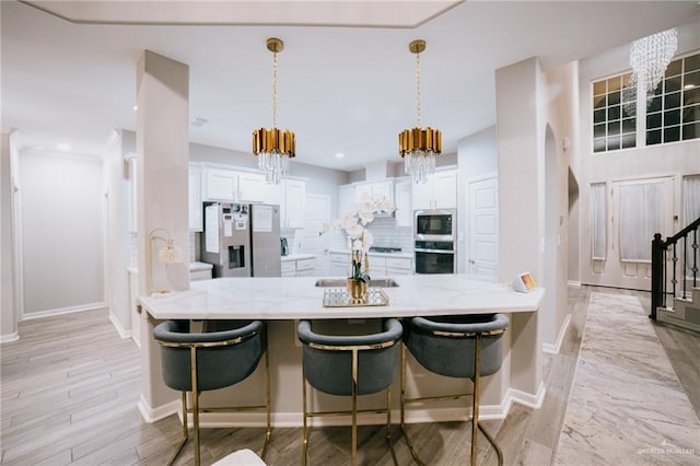 kitchen featuring pendant lighting, backsplash, appliances with stainless steel finishes, white cabinetry, and kitchen peninsula