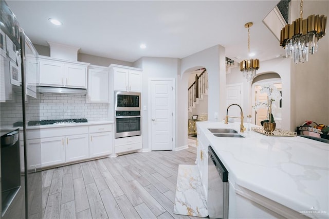 kitchen featuring pendant lighting, sink, light hardwood / wood-style flooring, appliances with stainless steel finishes, and white cabinetry