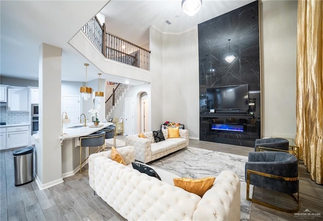 living room with ornamental molding, sink, and light hardwood / wood-style flooring