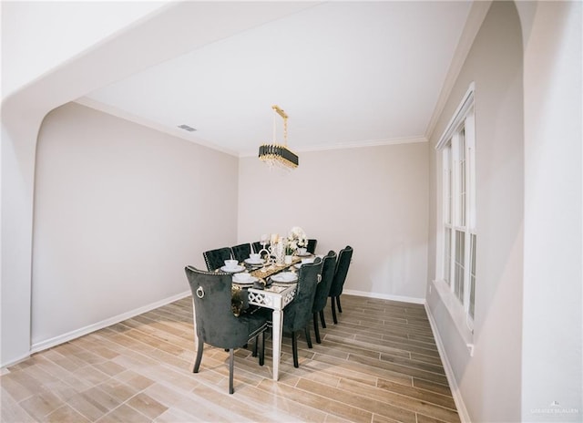 dining area with hardwood / wood-style floors, ornamental molding, and a chandelier