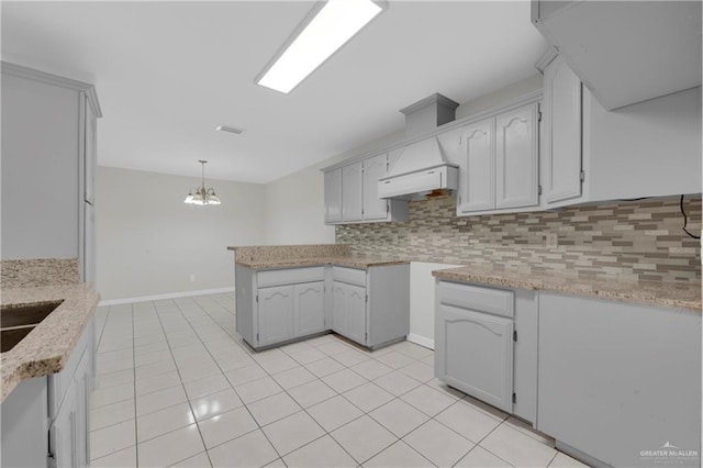 kitchen featuring backsplash, a chandelier, decorative light fixtures, light tile patterned floors, and custom exhaust hood