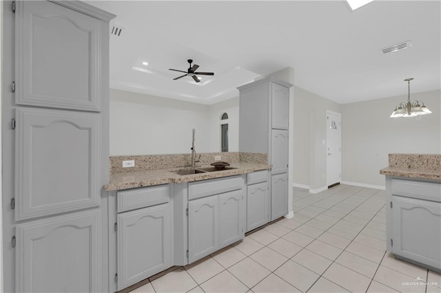 kitchen with white cabinets, sink, light tile patterned flooring, and ceiling fan with notable chandelier