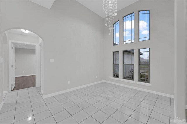 tiled empty room with a chandelier and a high ceiling