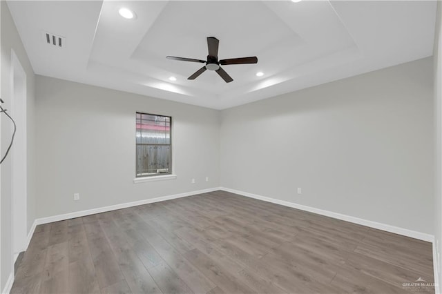 spare room featuring ceiling fan, a raised ceiling, and light hardwood / wood-style flooring