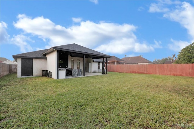 back of property with a yard, a patio, ceiling fan, and exterior kitchen