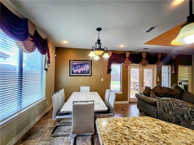 dining space featuring dark tile patterned flooring and a notable chandelier