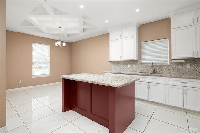 kitchen with a sink, decorative backsplash, a kitchen island, and coffered ceiling