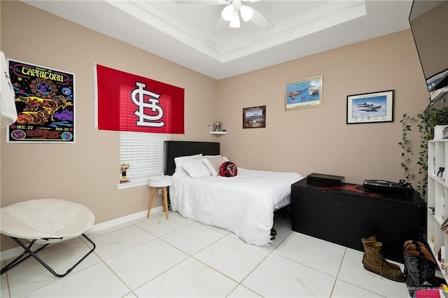 bedroom featuring baseboards, a raised ceiling, and ceiling fan